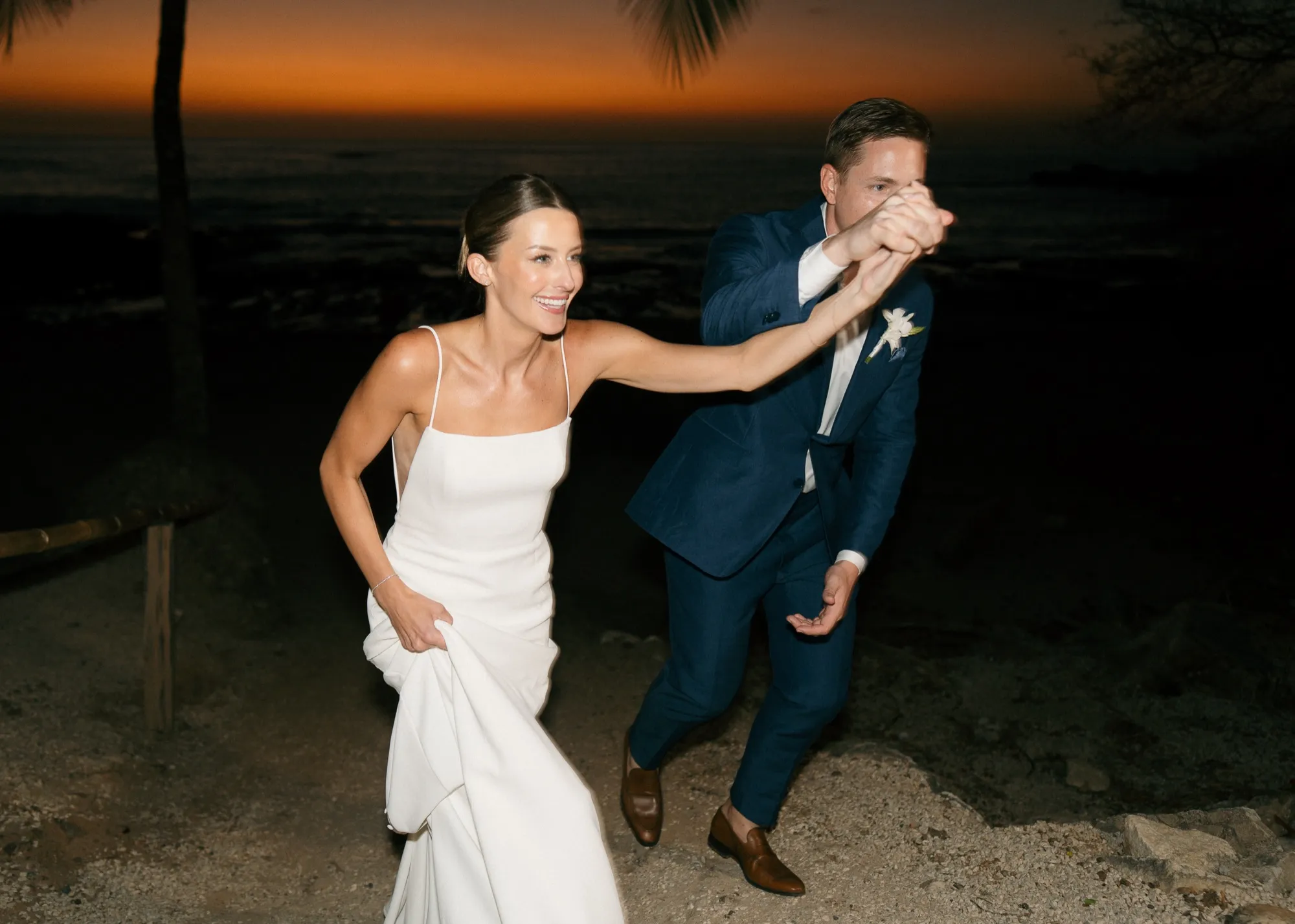 Newlyweds dancing against a vivid orange sunset on the beach in Nosara