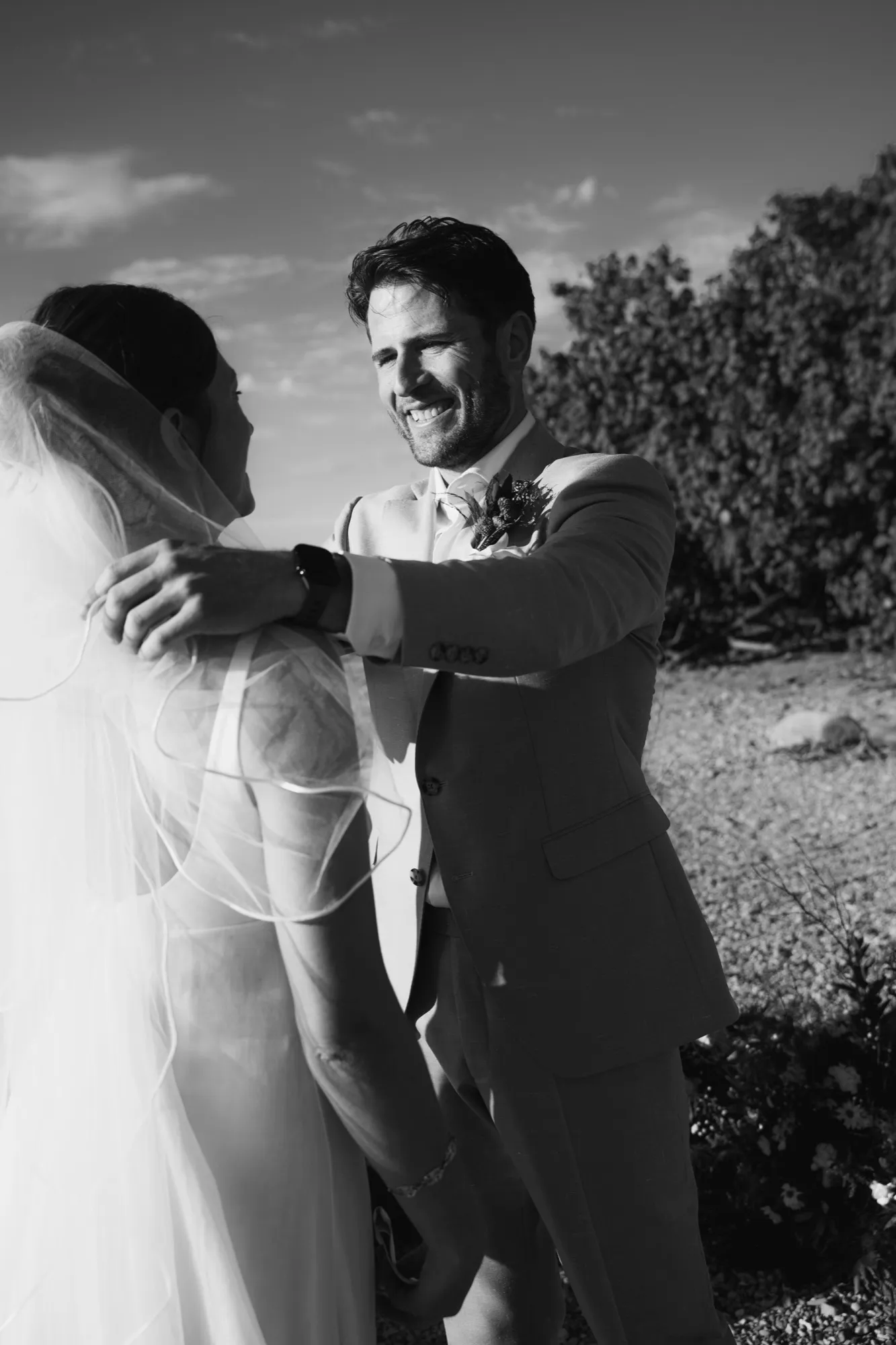 A couple embracing in black and white, the groom laughing, by the Nosara coast