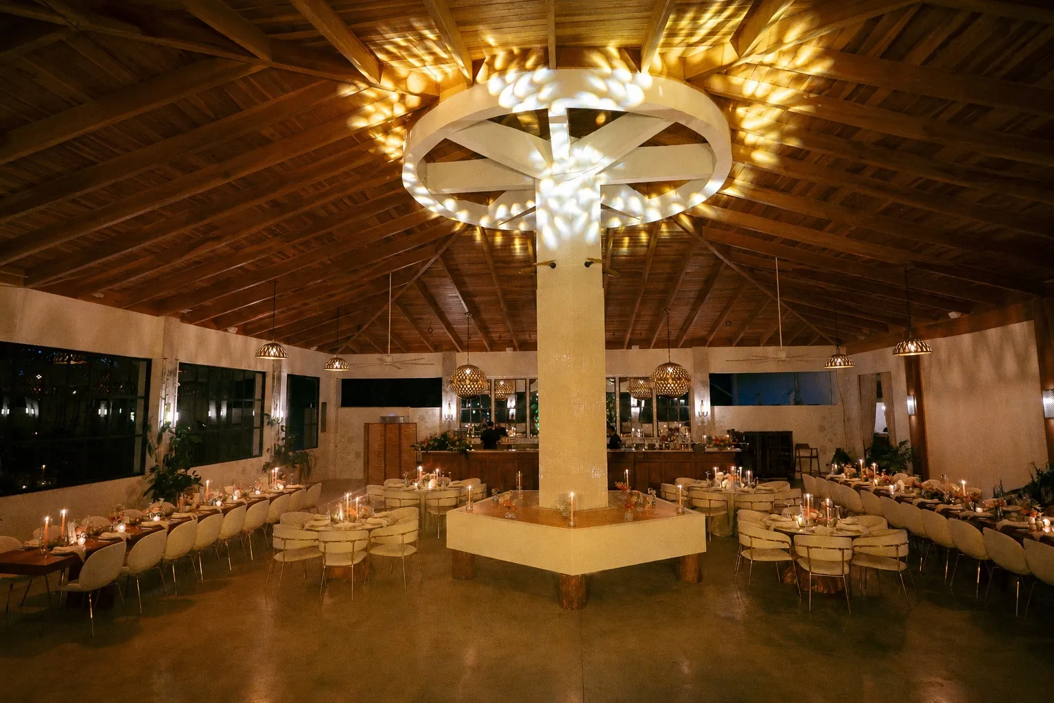 A Nosara reception hall under a timber ceiling and chandelier, set for dinner