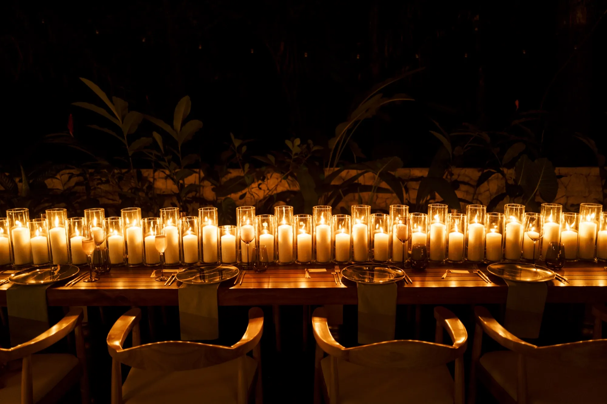 Rows of pillar candles lining a long reception table at night
