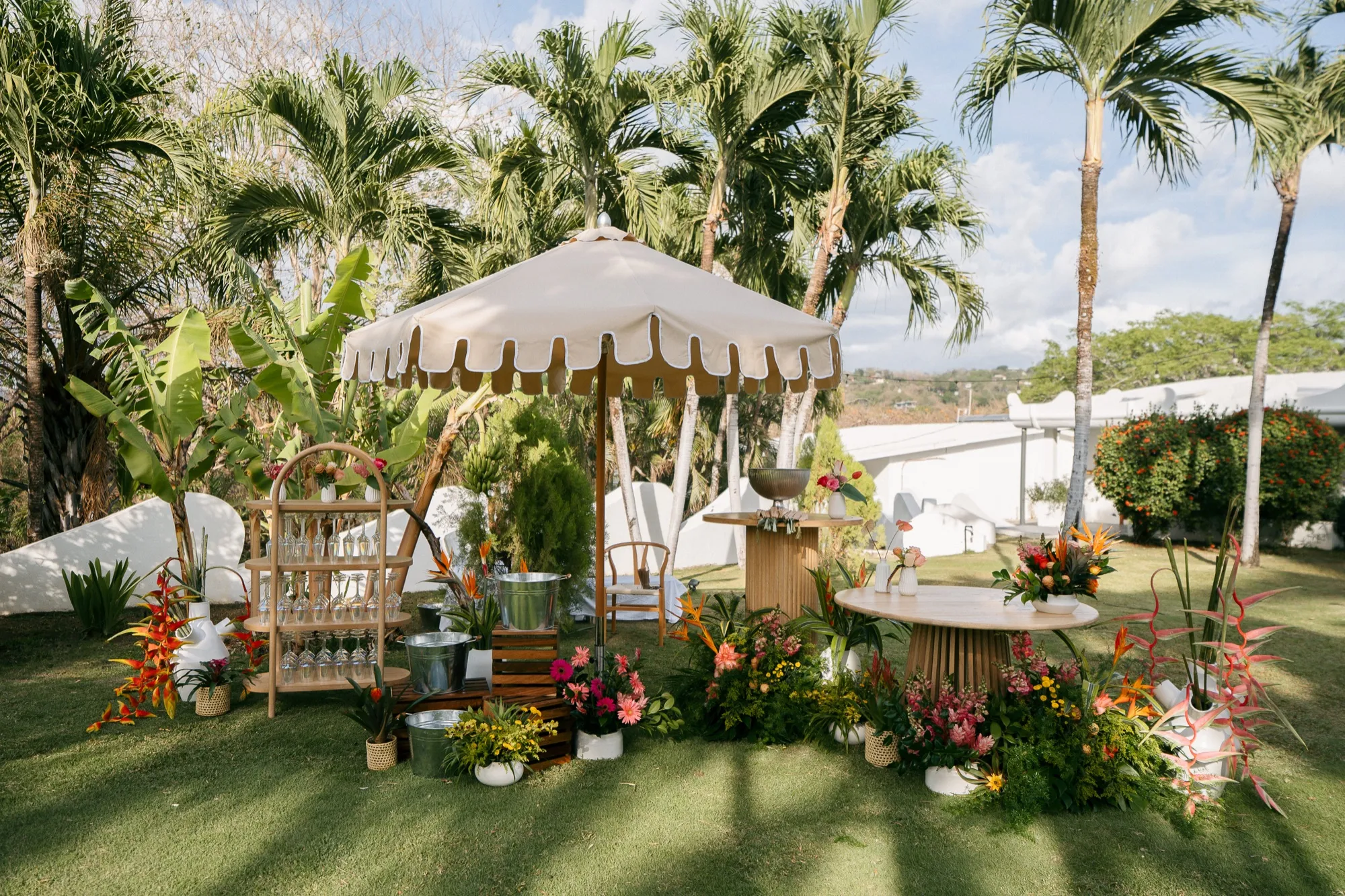 A styled garden bar and lounge with parasol and tropical florals at a Nosara wedding
