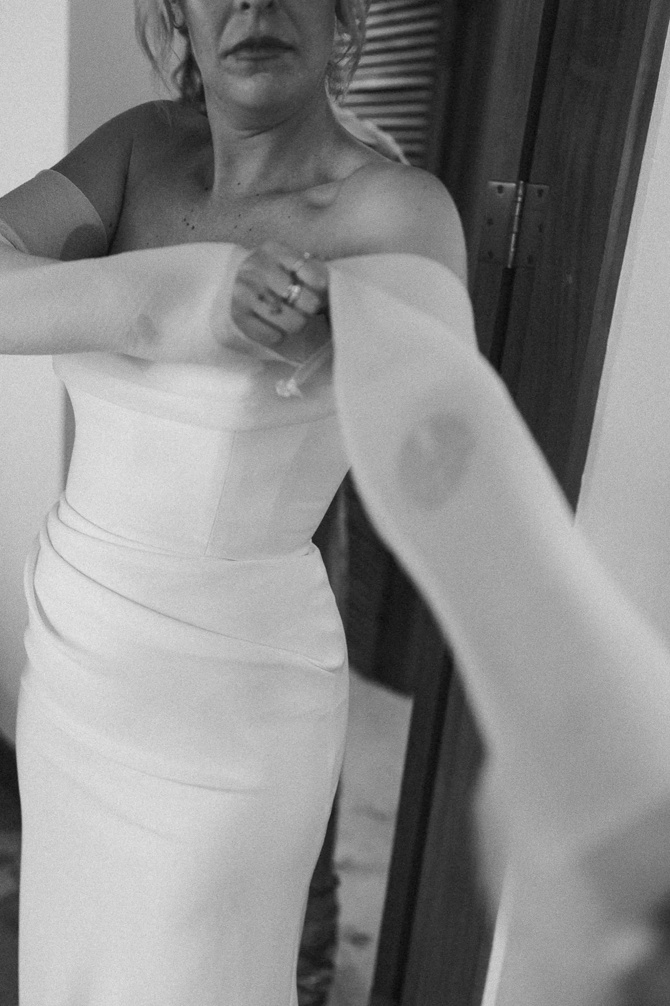 A black-and-white detail of a bride in her gown getting ready