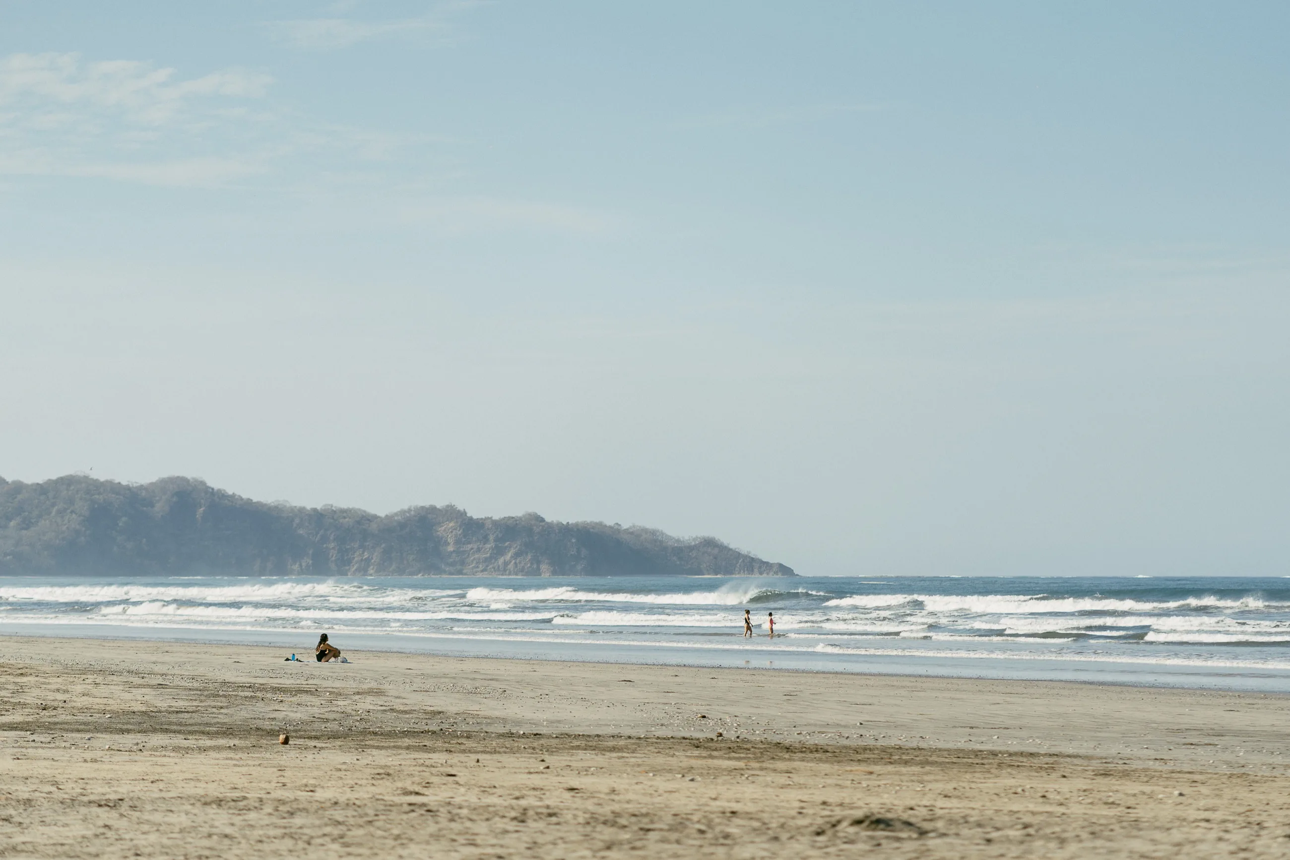 A quiet morning on the long beach at Nosara, Costa Rica, gentle surf and the headland beyond