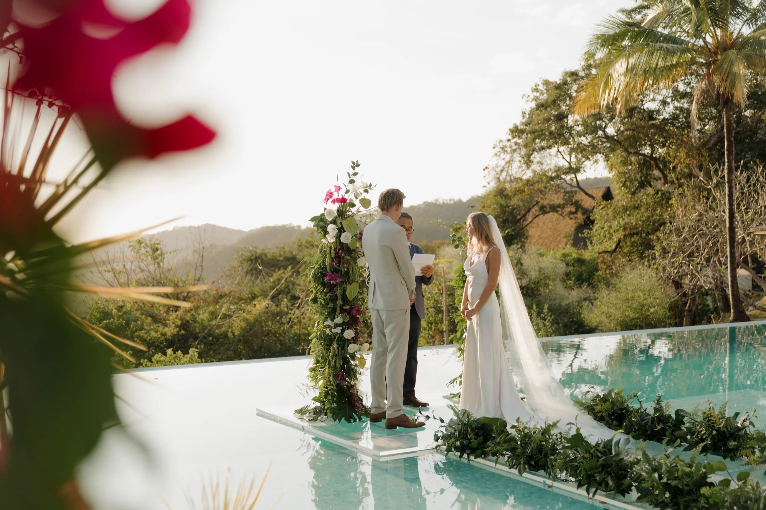 A couple exchanging vows on a platform over an infinity pool, framed by jungle and palms above Nosara, Costa Rica