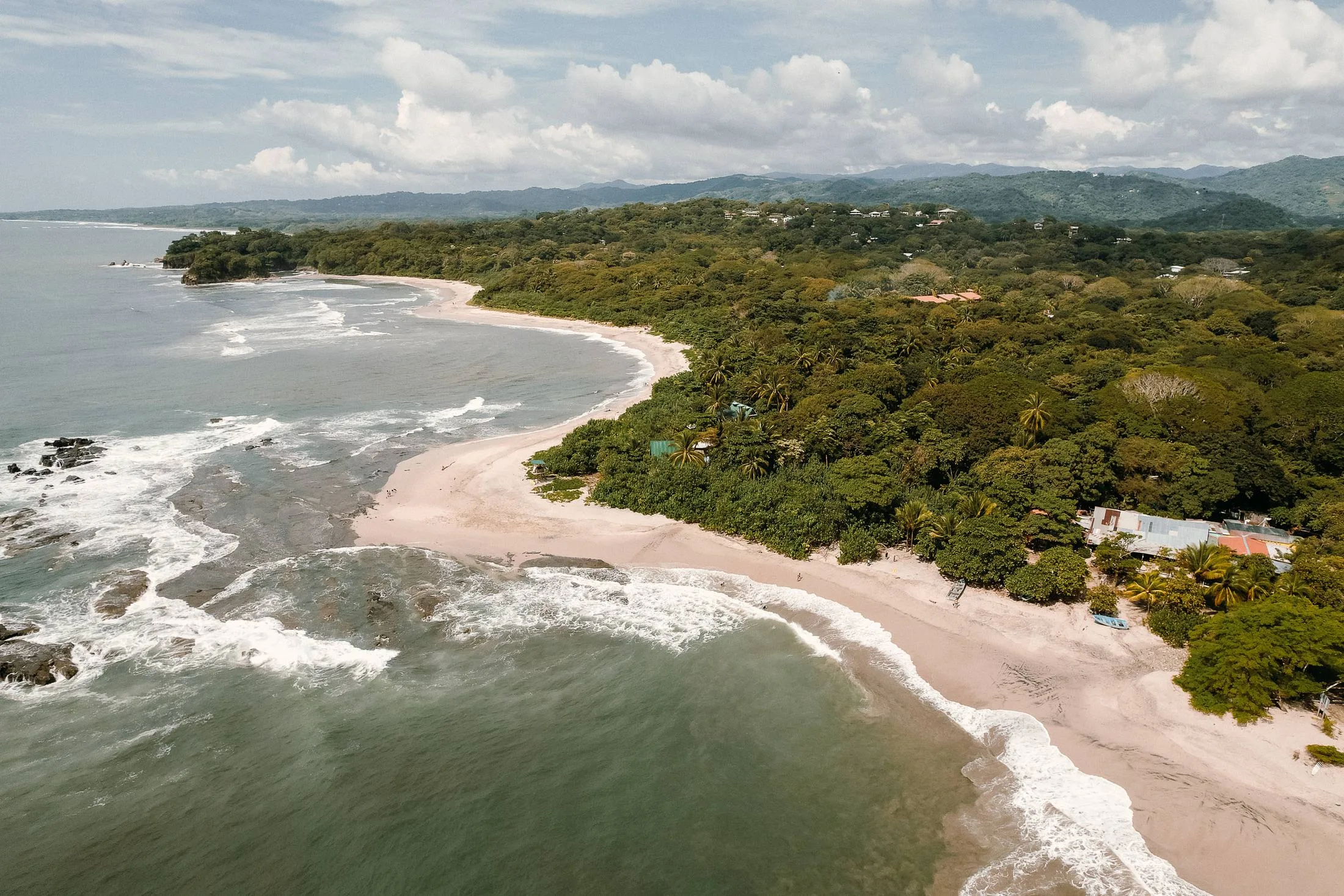An aerial view of the Nosara coastline, jungle running down to a long curve of Pacific beach