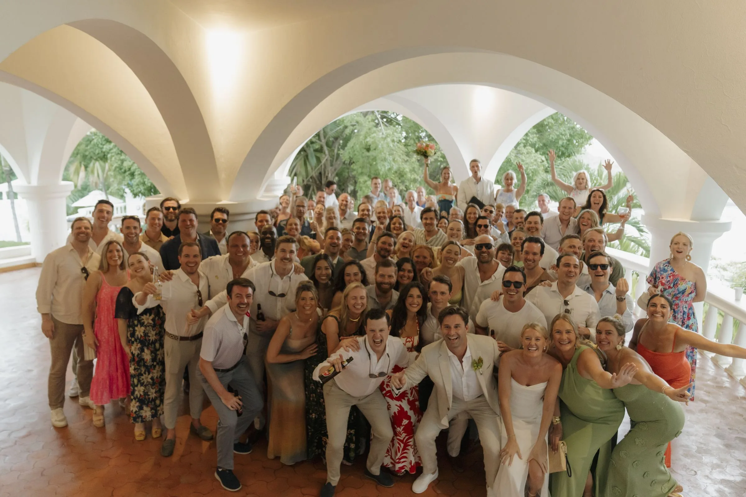 The whole wedding party gathered under the arches of a Nosara villa for a group portrait