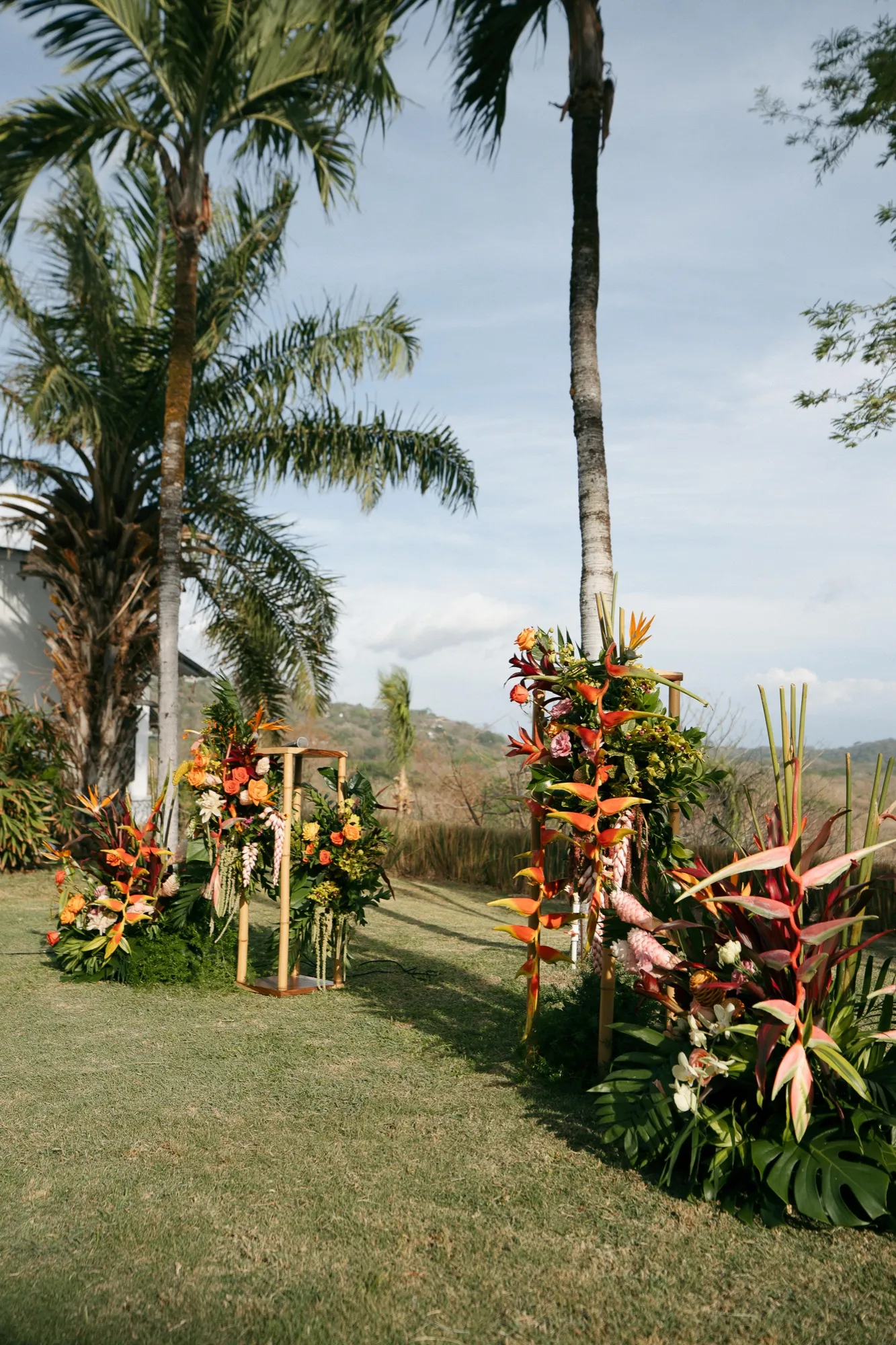 A tropical ceremony installation of heliconia, birds of paradise, and palms at a Nosara wedding